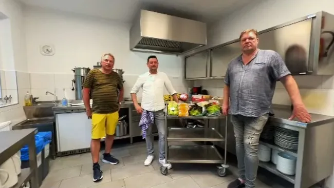 Drei ehrenamtliche Helfer mit frischem Gemüse in der Küche